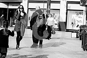 People shopping on Patrick Street in Cork, the main street for stores, street performers, restaurants; photographed in monochrome.