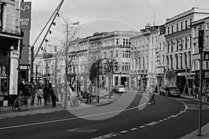 People shopping on Patrick Street in Cork, the main street for stores, street performers, restaurants; photographed in monochrome.