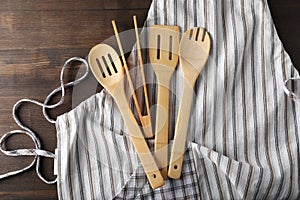 Apron with kitchen utensil on wooden background