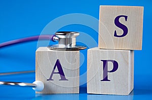 APS - acronym on wooden large cubes on blue background with stethoscope