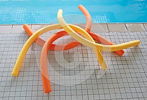 Aqua noodles next to a indoor swimming pool