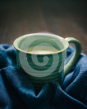 Aqua Pottery Mug Filled with Coffee and Nestled in a Denim Cloth