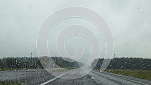 Ð¡ar is moving on road in rainy weather. Raindrops trickle down the windshield, which has nanocoating