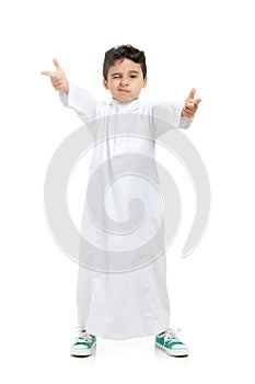 Arab boy winking and acting cool with crossed hands, wearing white traditional Saudi Thobe and sneakers, on white isolated photo