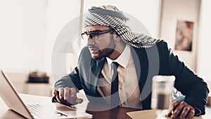 Arab businessman peering at laptop at table