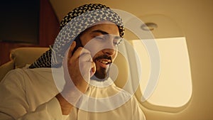 Arab businessman talking cell phone in airplane closeup. Confident man traveling