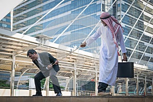 Arab businessmen and businessman playing tug of war on city back