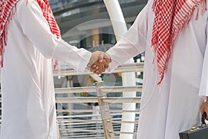 Arab businessmen shaking hands together in modern city