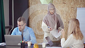Arab and caucasian woman are discussing and taking paper in modern office