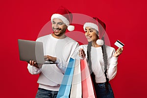 Arab Couple In Santa Hats Shopping Online With Laptop And Credit Card