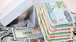 Arab Currency Dirhams in White Gift Box on a Background of American Dollars Bank notes on Rotating Table.