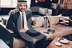 Arab drinking coffee on couch in office