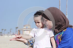 Arab egyptian muslim mother with her baby girl on beach in egypt
