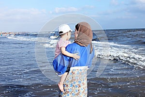 Arab egyptian muslim mother holding her baby girl on beach in egypt