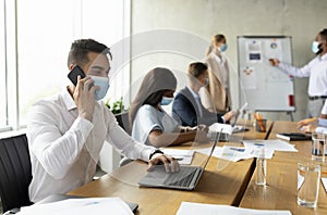 Arab Employee Wearing Mask Using Laptop And Cellphone During Meeting With Colleagues