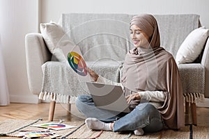 Arab Female Designer Sitting With Laptop And Color Swatches On Floor