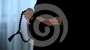 Arab female in hijab counting prayers by rosary in hand, religious forgiveness