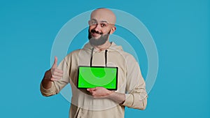 Arab guy holding device with greenscreen blank display