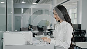 Arab hispanic businesswoman girl worker secretary makes copies on photocopier use office equipment print machine
