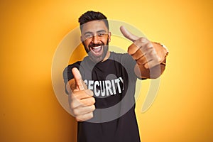 Arab indian hispanic safeguard man wearing security uniform over isolated yellow background approving doing positive gesture with