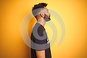 Arab indian hispanic safeguard man wearing security uniform over isolated yellow background looking to side, relax profile pose