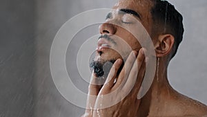 Arab indian man bearded guy naked male washes head with shampoo washing hair face and beard in bathroom showering in at