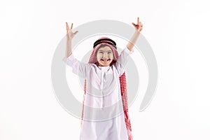 Arab joyous boy in keffiyeh puts hands up.
