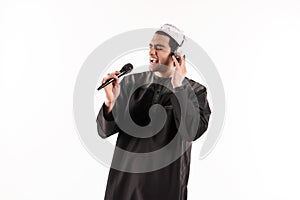 Arab male in ethnic dress is singing in karaoke.