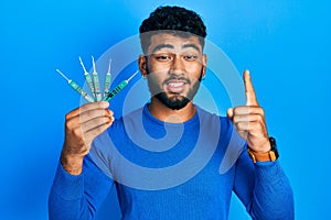 Arab man with beard holding picklock to unlock security door smiling with an idea or question pointing finger with happy face,