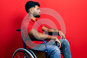 Arab man with beard sitting on wheelchair looking to side, relax profile pose with natural face and confident smile