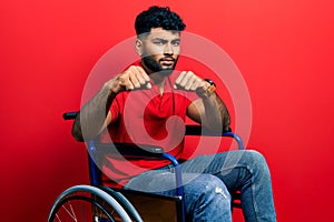 Arab man with beard sitting on wheelchair punching fist to fight, aggressive and angry attack, threat and violence
