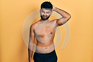 Arab man with beard wearing swimwear shirtless confuse and wonder about question