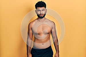 Arab man with beard wearing swimwear shirtless skeptic and nervous, frowning upset because of problem