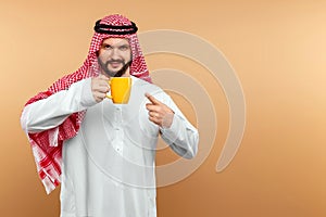Arab man businessman in national dress holds a cup in his hands. Dishdasha, kandora, thobe, middle east traditional menswear photo
