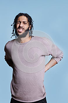 Arab man having lower backache with grimace on face