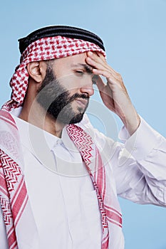 Arab man with headache holding forehead
