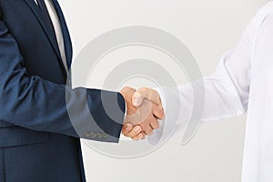 Arab man and his business partner shaking hands on grey background