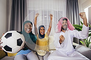 Arab man looking TV at home during a sport event with his family.