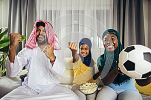 Arab man looking TV at home during a sport event with his family.