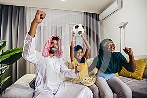 Arab man looking TV at home during a sport event with his family.