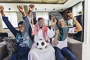 Arab man looking TV at home during a sport event with his family.