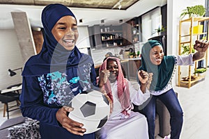 Arab man looking TV at home during a sport event with his family.