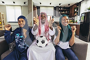 Arab man looking TV at home during a sport event with his family.