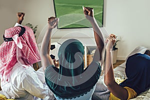 Arab man looking TV at home during a sport event with his family. Watching football game