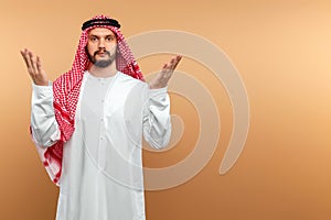 An Arab man in national dress is praying on a beige background. Dishdasha, kandora, thobe ,, traditional men`s clothing of the