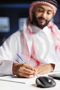 Arab man sits at the table and writes
