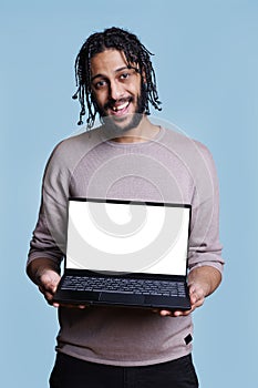 Arab man standing with laptop showing blank screen