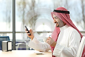 Arab man texting in a smart phone in a bar