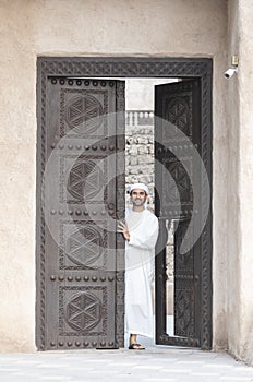 Arab man in traditional clothing coming out of a door