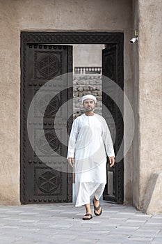 Arab man in traditional clothing coming out of a door